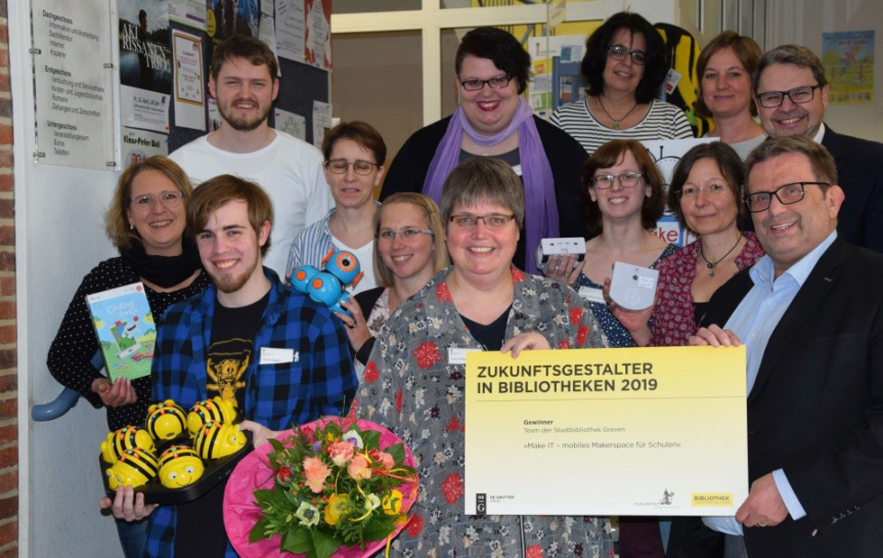 Abb. 1 
        Foto des Bibliotheksteams mit Bürgermeister Peter Vennemeyer, Erstem Beigeordneten Cosimo Palomba und Medienberaterin Katja Möhring
      
