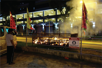 Figure 34: A migrant worker watching the flames die down.