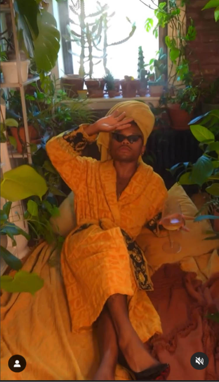 Figure 8
@plantkween sits luxuriously against a plant-filled backdrop in a relaxed pose, wearing a bathrobe, head towel, and black heels.