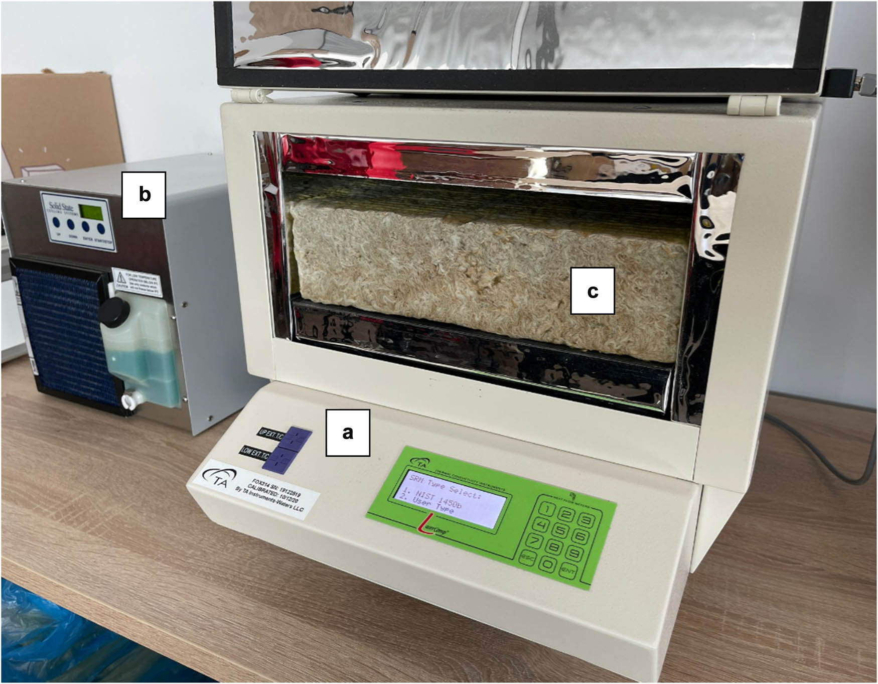 Figure 4 
               Photograph of the measurement stand: (a) plate apparatus for testing thermal conductivity, (b) refrigerator stabilizing the temperature of the hot plate, and (c) test sample (own source).
            