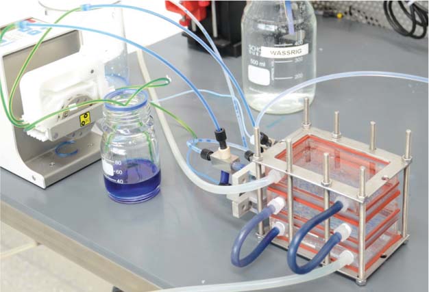 Figure 13 Complete two-stage counter-current setup with pumps, tubes and flask for organic (blue color) and aqueous phases.The tubes for the temperature control fluid are visible at the front side of the stack.