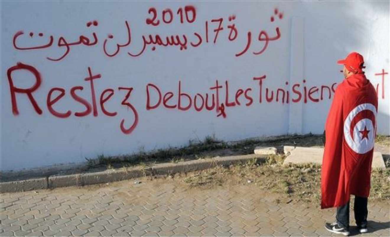 Figure 3: 
A Tunisian man reading graffiti. Translation of the Arabic text: “The Revolution of 17 December will never die”.
