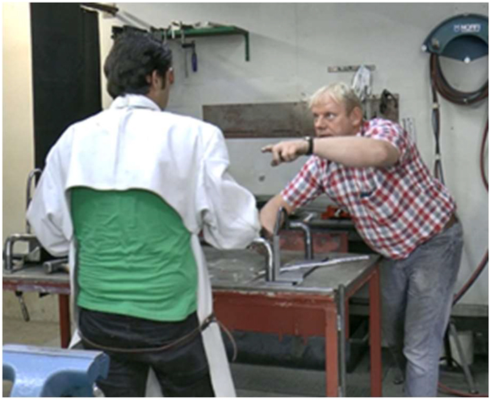 Figure 3: 
Trainee stands up still facing the instructor, who continues pointing.
