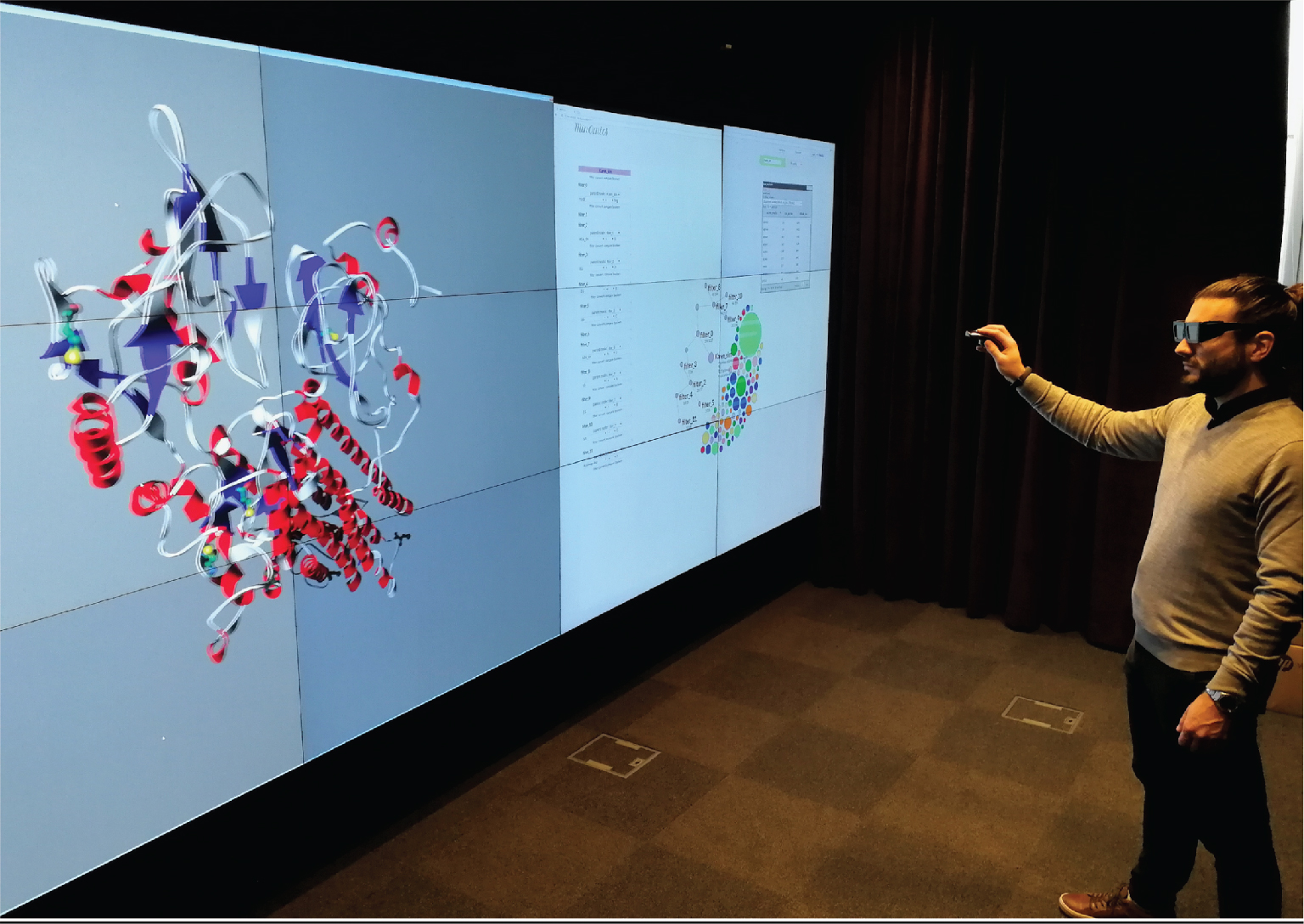 Figure 8: Split-screen setup with stereoscopy. Example of MinOmics running on a web browser on the right half of the display wall, linked to a 3D stereoscopic rendering via UnityMol filling the left half. A gyroscopic mouse is used to operate the system and interact with all elements.