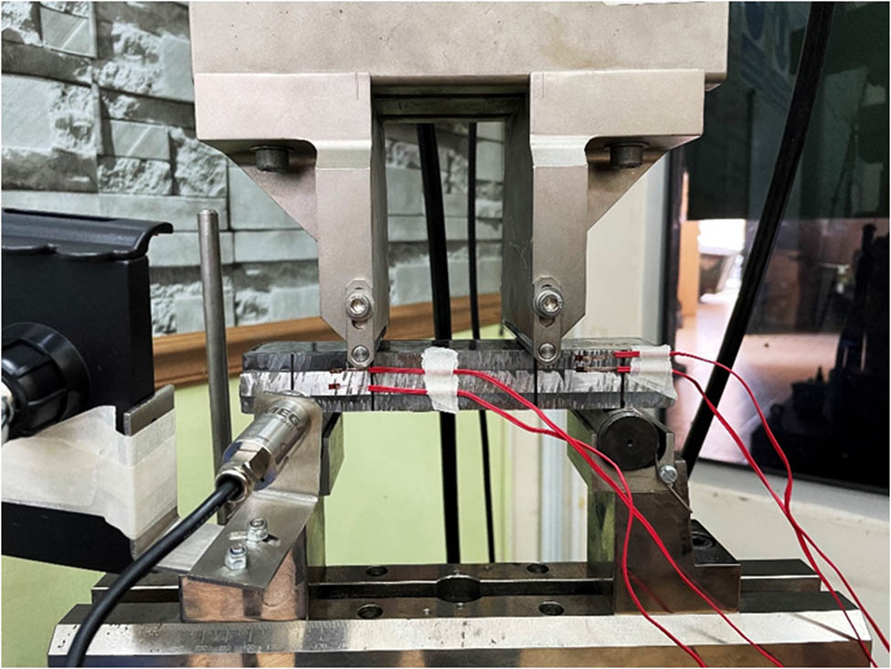 Figure 9 
                  The metal sandwich panel specimen in the four-point bending setup with the strain gauge at the bonding area of the metal sandwich panel attached to the data acquisition system.
               