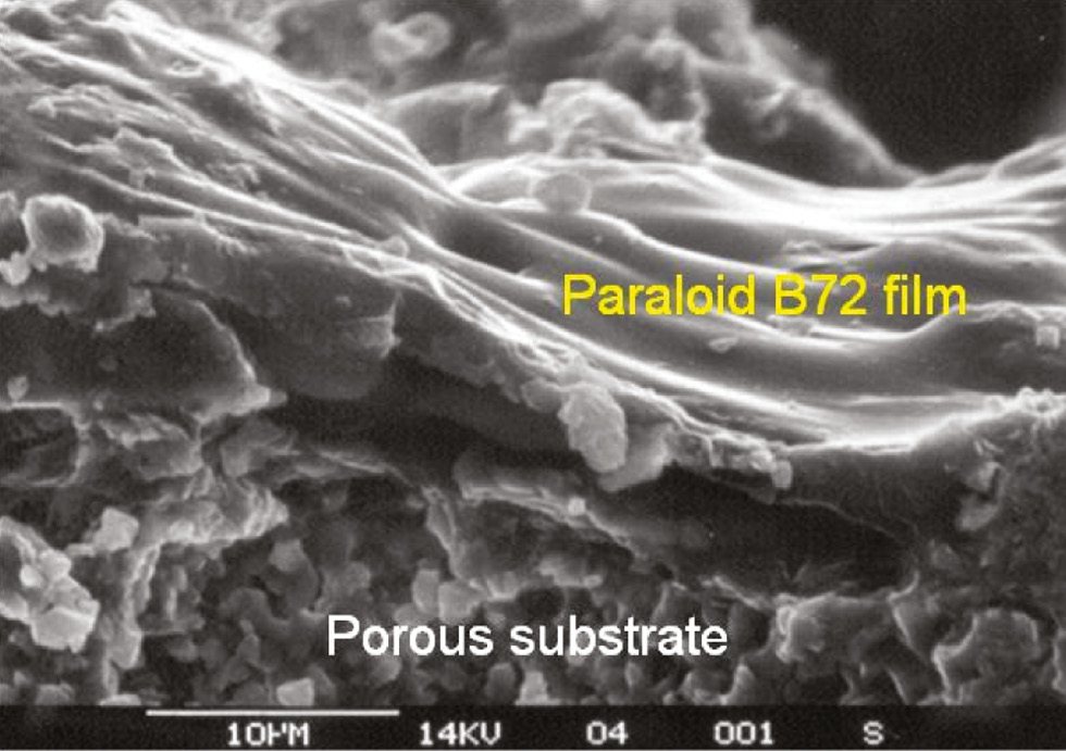 Fig. 2: 
          SEM image of a cross-section of calcarenite (limestone) from the Cathedral of Granada treated with an acrylic copolymer (Paraloid B72). The copolymer forms an impervious (detrimental) surface film.
        
