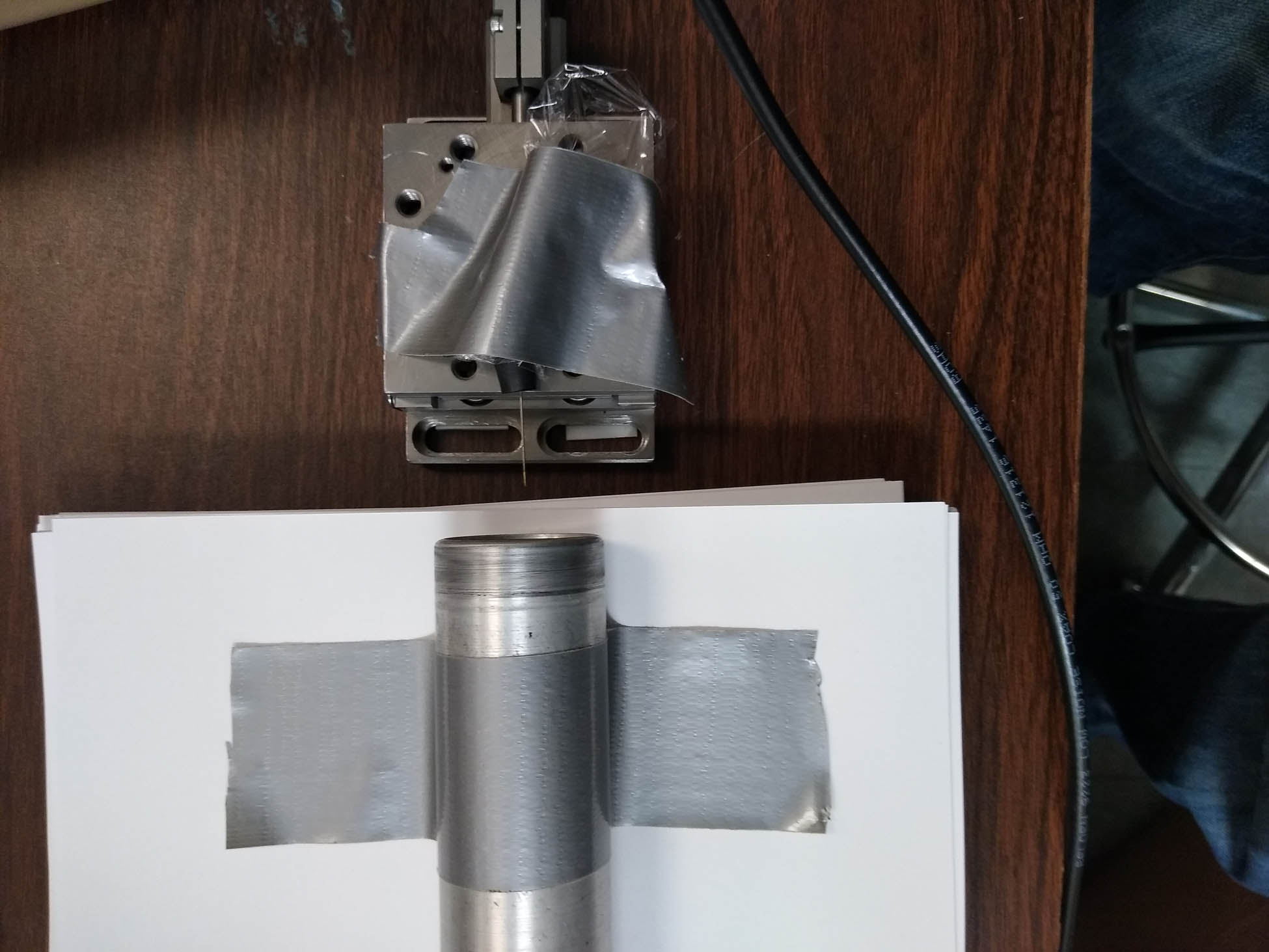 Figure 1 
               Test of experimental concept. The GM tube is the cylinder in the bottom half of the photograph. One can make out the very thin source needle issuing from the plug at the lower edge of the movable stage in the top half of the photograph.
            