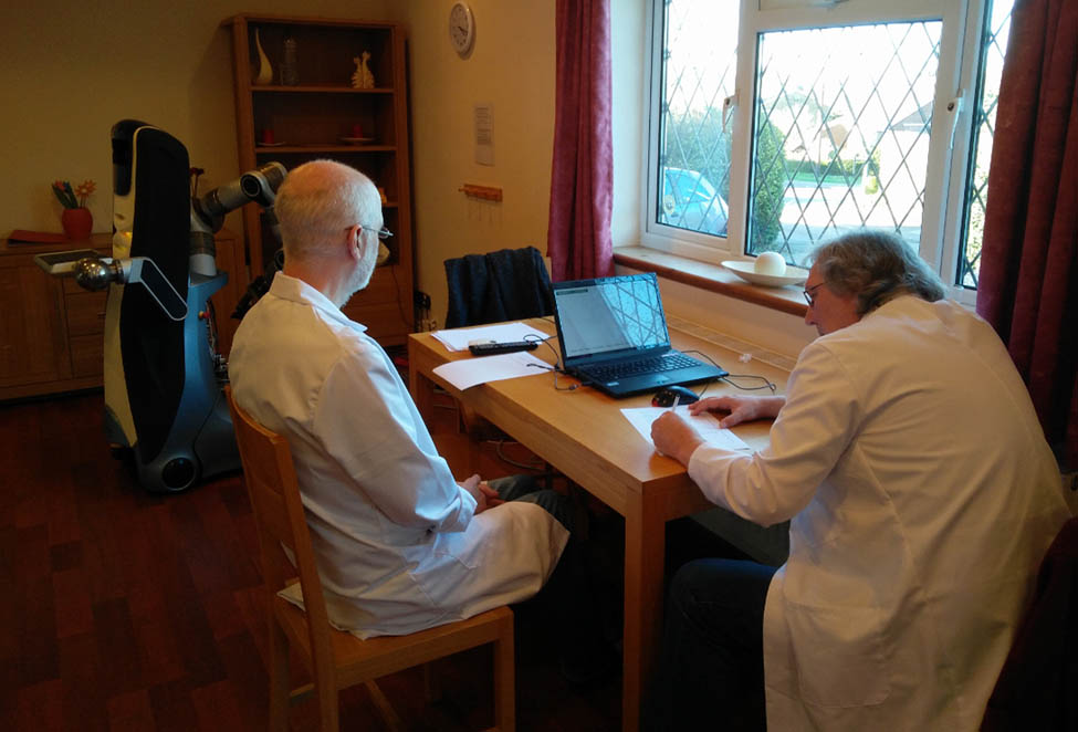 Figure 8 
                     Training in progress. The experimenter is facing the window, the participant is facing the laptop computer with the teachMe system running. The Care-O-bot3® robot is present in the background.
                  