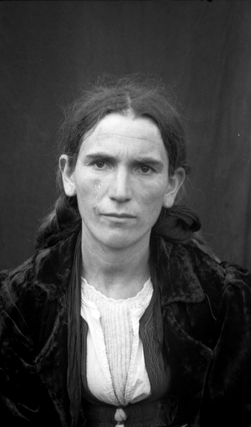 Figure 8: 
Identity photograph taken by Filip Vito in Fushëbardhë, 1948. Courtesy: Private collection, Paris. One of 35 portraits on a film kept by the photographer’s family. The picture was taken outdoors, against a backdrop fixed to a wall. The subject was asked to remove her scarf (which can be seen at the back of her head) and is seen wearing a coat that appears in other pictures of the same series.